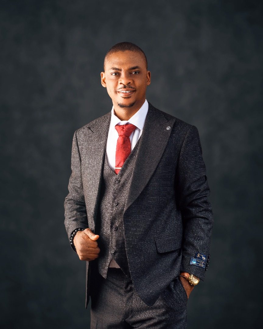 Dr. Amao in a charcoal three-piece suit and red tie
